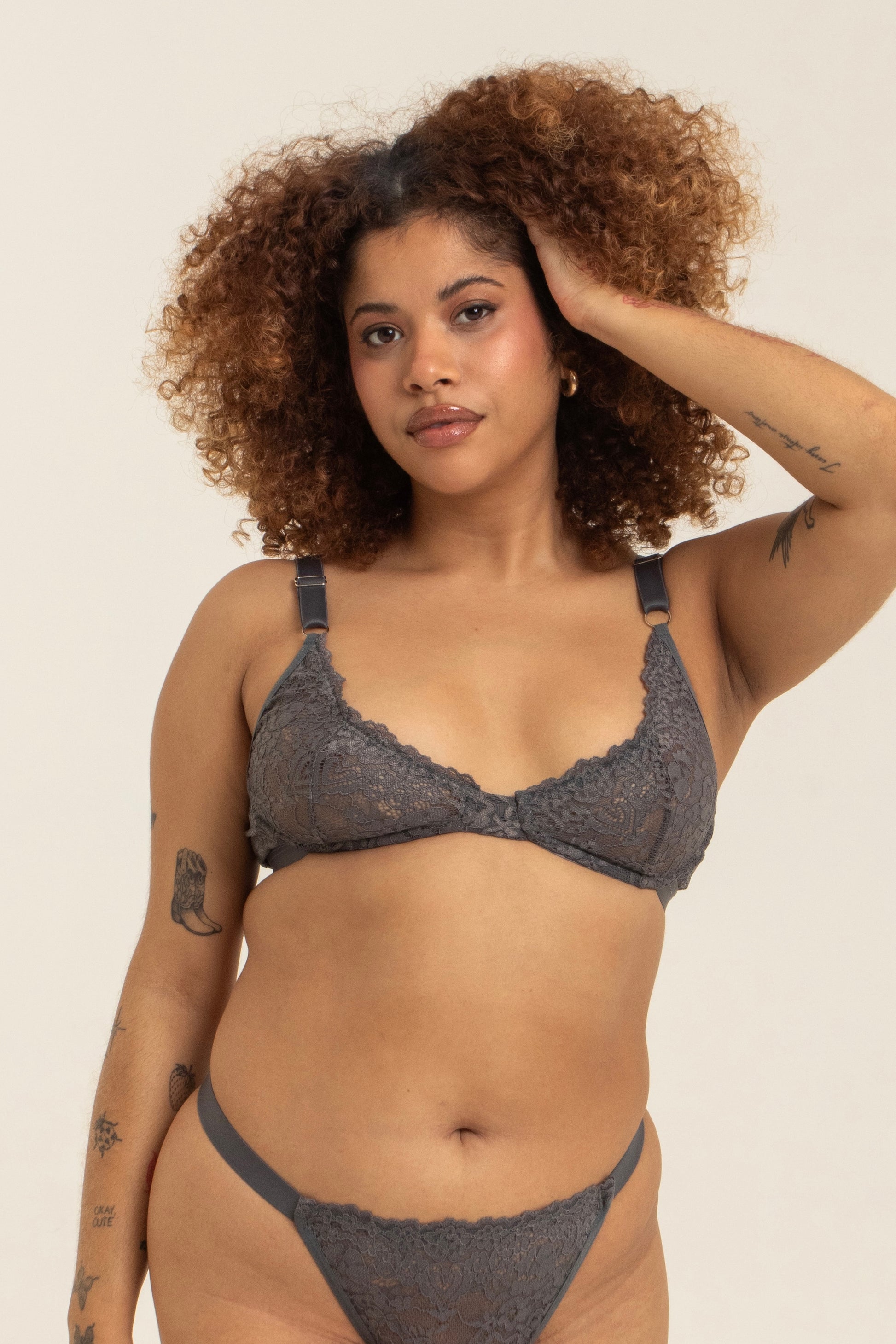 modelo veste sutiã em renda plus size na cor cinza, com taça que abraça até a lateral do peito e trás efeito push up